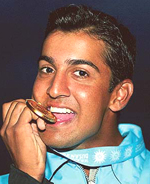 Indias Shiv Kapur bites his gold medal after winning the golf final 