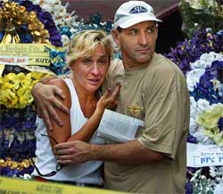 Stuart Cram comforts his sister Tia Byron from Sydney, Australia, who is the mother of a 14-year-old victim, Chloe Byron