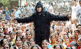 A Shiv Sena activist dressed as a scarecrow entertains party workers
