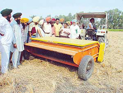Operation of the paddy straw chopper being explained to farmers at PAU farms in Ludhiana on Wednesday.