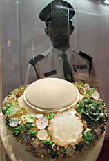 A security guard stands behind a gold medal award jewelry set