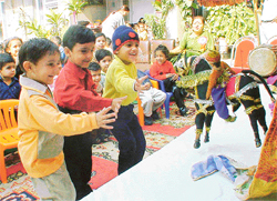 Kids enjoy a puppet show at Kids Carnival in St Xavier Playway School
