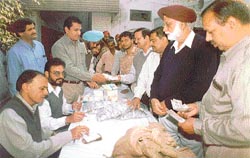 Employees of Uco Bank, Chaura Bazar, distribute new currency notes and coins
