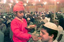 A Sikh boy offers a sweet to a Muslim devotee