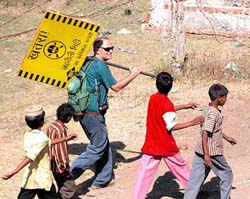 A member of the Green Peace holding a sign board goes to instal it at the site of the Union Carbide factory premises