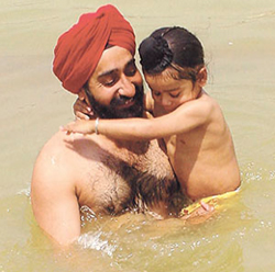 A devotee takes a dip with his son in the sarovar at Gurdwara Rakab Ganj Sahib 