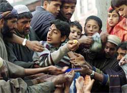 A Kashmiri boy distributes rice to Muslim villagers