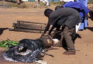 Nigerian men remove charred remains of one of the dead bodies