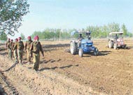  a police party patrols the fields that were ploughed before the possession was handed back to the Panchayat