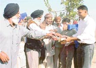 A villager distributes sweets among other villagers after the possession of a disputed land was returned to the Panchayat, in Bhupana village