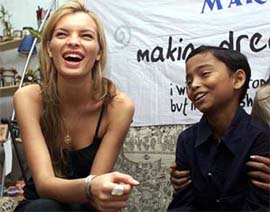 Spanish model Esther Canadas laughs as she sits beside an Indian boy