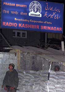A soldier stands guard under the sign board of Kashmir's Radio Station