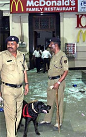 Policemen stand guard after a blast outside a McDonalds restaurant in Mumbai 
