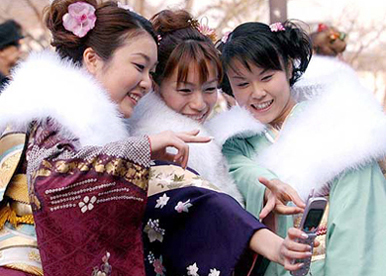 Dressed up in traditional kimonos, Japanese women take pictures by a mobile phone with a camera 