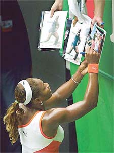 Serena Williams of the USA signs autographs after her win