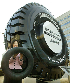 An employee of Japanese tyre maker Bridgestone holds an ordinary size tyre