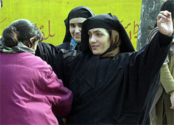 A lady cop in plainclothes frisks a Kashmiri woman 