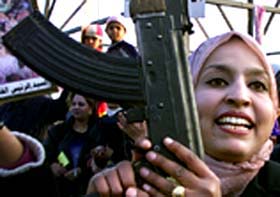 An Iraqi woman carrying a gun takes part in a demonstration in support of President Saddam Hussein 