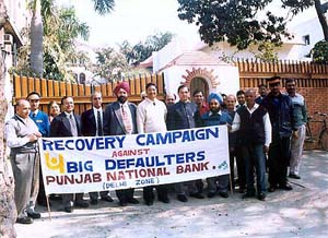 Punjab National Bank officials demonstrate in front of loan defaulters' houses