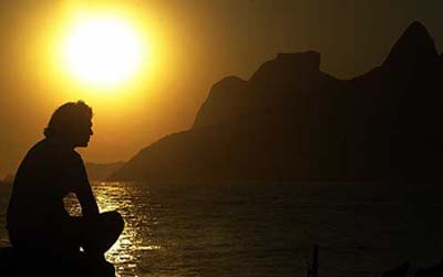 A surfer pauses to watch sunset at Ipanema beach in Rio de Janeiro