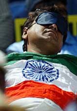 A disappointed Indian cricket fan with the national flag on his chest covers his eyes