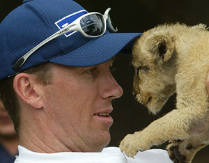 Australian bowler Glenn McGrath holds a one-week-old lion cub up to his face 