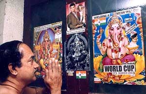 Cricket fan Rama Krishnan prays in front of a collaged poster featuring Lord Ganesh and references to the cricket World Cup