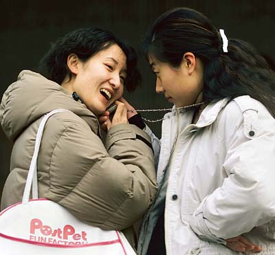 Chinese women chat on a mobile phone in Beijing.