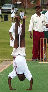 A young schoolboy does a somersault down the pitch at a cricket clinic