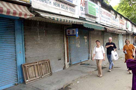 Commuters walk past closed shops at Janpath
