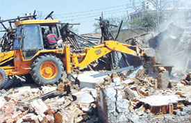 A bulldozer in operation at Lakri market in Azadpur area pulling down structures