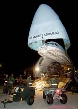 Members of the US Air Force load equipment, including an HH-60G Pave Hawk helicopter, onto a C-5 Galaxy transport plane