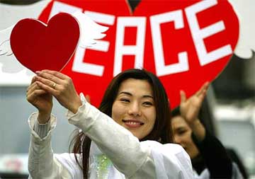 A South Korean woman dressed as an angel holds a heart during a rally