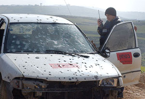 A policeman looks at the car in which two Israeli armed guards were killed by Israeli soldiers in a friendly-fire incident 