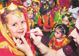 A teacher gives finishing touches to a childs makeup during the annual day function of Love Dale School