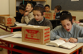 Ultra-orthodox Jewish students sit at their desks with their gas masks on as precautions in case of an attack on Israel