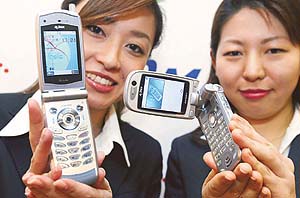 Employees from Japans NTT DoCoMo Inc display the FOMA P2102V (R), its first 3G videophone handset capable of video clip e-mailing