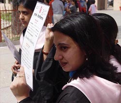 A young graduate holds her degree as a shield against the scorching sun
