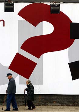 An elderly Chinese couple walk past a billboard promoting a new commercial building in Beijing