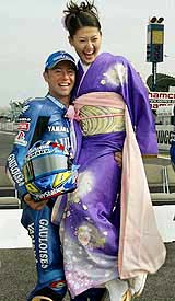 MotoGP rider Olivier Jacque of France lifts up a kimono-clad hostess during a photo session 