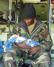 Chief hospital corpsman David Jones of the 15 Marine Expeditionary Unit holds two-hour-old newborn Rogenia Katham