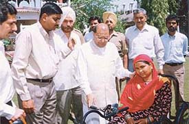 Dr Ramesh Dutt Sharma, Minister for Removal of Grievances, Pension and Cooperation, Punjab, gives a tricycle to a disabled woman