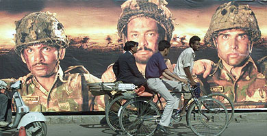 A rickshaw-puller pedals past an advertisement hoarding