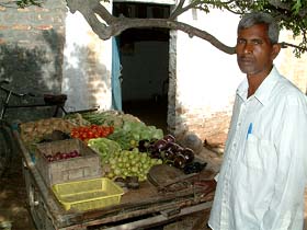 Kashi Prasad, father of district topper Pooja Rani, stands beside his rehri