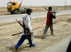 Iraqi men hold weapons looted from a police station at Saddam city in Baghdad
