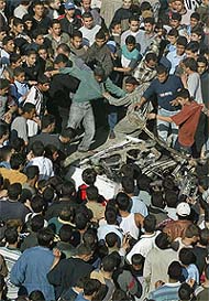 Palestinians inspect damage to a car after it was hit by a missile from Israeli helicopters in Gaza 