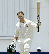 Australia's Justin Langer raises his bat after reaching his century against the West Indies 
