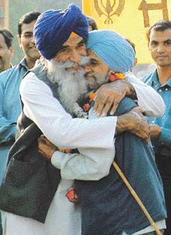 Sham Singh, co-chairman of the PSGPC, hugs an Indian Sikh at the  Wagha checkpost. --- Photo Rajiv Sharma
