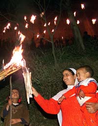 A Kashmiri woman with her children burn torches during the annual festival at the shrine of the Sufi Saint Sakhi Zain-ud-din Wali