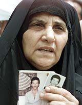 An Iraqi woman holds up pictures of her sons